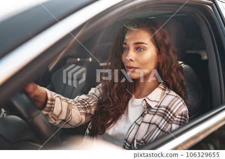 Portrait of a beautiful smiling woman in a car looking out of the window 106329655
