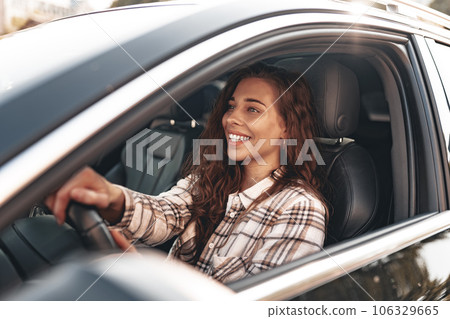 Young smiling woman driving a car in the city Young smiling woman driving a car in the city 106329665