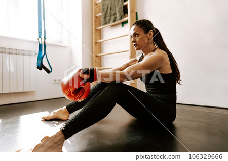 Fit woman in sportswear and red boxing gloves in a gym Fit woman in sportswear and red boxing gloves in a gym 106329666