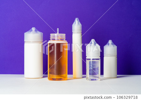 Electronic cigarettes liquid bottles on purple background 106329718