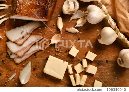 still life of food in a rural style on a dark wood background, sliced lard and garlic, cheese and onion, concept of fresh vegetables and healthy food still life of food in a rural style on a dark wood background, sliced lard and garlic, cheese and onion, concept of fresh vegetables and healthy food 106330040