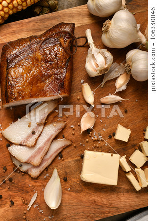 still life of food in a rural style on a dark wood background, sliced lard and garlic, cheese and onion, concept of fresh vegetables and healthy food 106330046