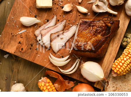 still life of food in a rural style on a dark wood background, sliced lard and garlic, cheese, corn and onion, concept of fresh vegetables and healthy food still life of food in a rural style on a dark wood background, sliced lard and garlic, cheese, corn and onion, concept of fresh vegetables and healthy food 106330053