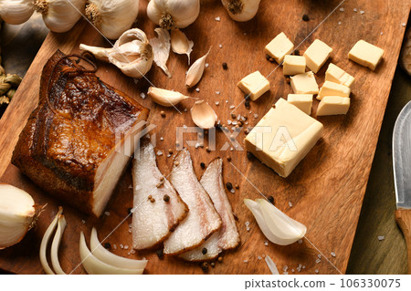 still life of food in a rural style on a dark wood background, sliced lard and garlic, cheese and onion, concept of fresh vegetables and healthy food 106330075
