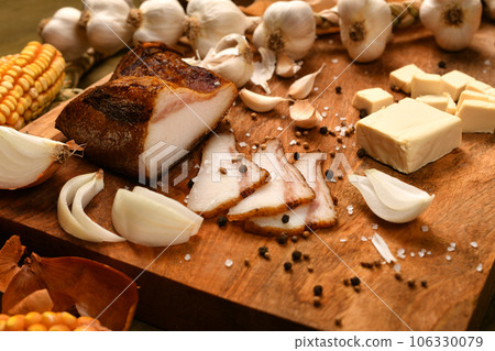 still life of food in a rural style on a dark wood background, sliced lard and garlic, cheese, corn and onion, concept of fresh vegetables and healthy food still life of food in a rural style on a dark wood background, sliced lard and garlic, cheese, corn and onion, concept of fresh vegetables and healthy food 106330079