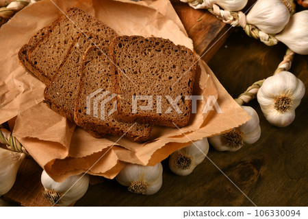 still life of food in a rural style on a dark wood background, rye bread and garlic, concept of fresh vegetables and healthy food still life of food in a rural style on a dark wood background, rye bread and garlic, concept of fresh vegetables and healthy food 106330094