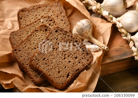 still life of food in a rural style on a dark wood background, rye bread and garlic, concept of fresh vegetables and healthy food still life of food in a rural style on a dark wood background, rye bread and garlic, concept of fresh vegetables and healthy food 106330099