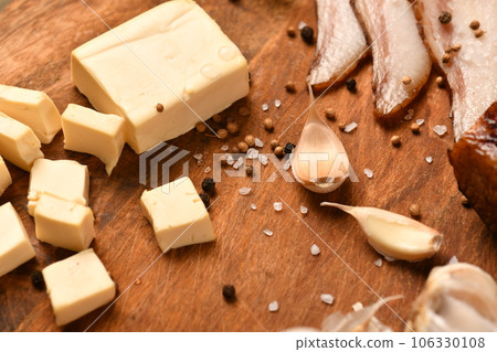 still life of food in a rural style on a dark wood background, sliced cheese and bacon, garlic, salt and pepper, concept of healthy food still life of food in a rural style on a dark wood background, sliced cheese and bacon, garlic, salt and pepper, concept of healthy food 106330108