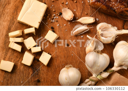 still life of food in a rural style on a dark wood background, sliced cheese and bacon, garlic, salt and pepper, concept of healthy food still life of food in a rural style on a dark wood background, sliced cheese and bacon, garlic, salt and pepper, concept of healthy food 106330112