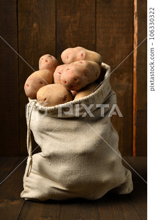 a sack full of potatoes on dark wooden background a sack full of potatoes on dark wooden background 106330322