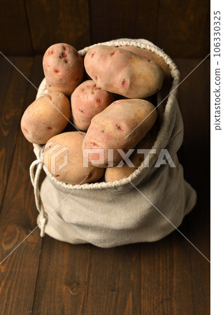 a sack full of potatoes on dark wooden background 106330325