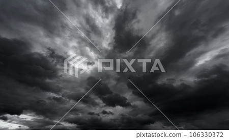 dark dramatic sky with black stormy clouds before rain or snow as abstract background, extreme weather, the sun shines through the clouds, high contrast photo 106330372
