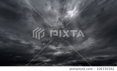 dark dramatic sky with black stormy clouds before rain or snow as abstract background, extreme weather, the sun shines through the clouds, high contrast photo 106330382