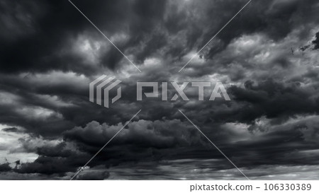 dark dramatic sky with black stormy clouds before rain or snow as abstract background, extreme weather, the sun shines through the clouds, high contrast photo 106330389