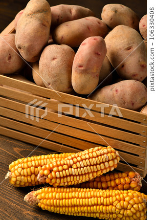 wooden box full of potatoes and corn cobs on dark wooden background wooden box full of potatoes and corn cobs on dark wooden background 106330408