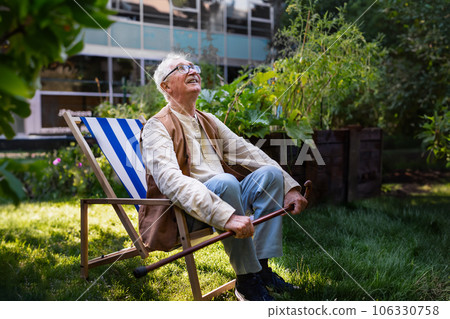 Portrait of smiling senior man resting after taking care vegetable plants in urban garden. 106330758
