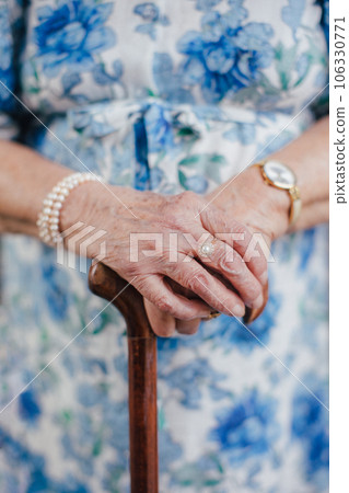 Close-up of a senior woman's hands holding a walking cane. 106330771
