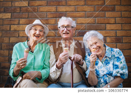 Portrait of three senior friends in the city, eating ice cream on a hot summer day. 106330774