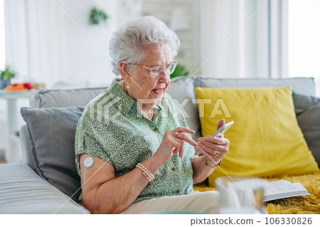 Senior diabetic woman checking her glucose data on smartphone. 106330826