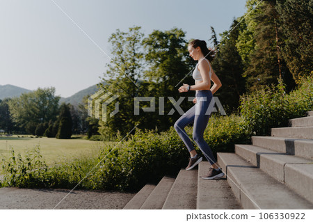 Sporty woman running down the concrete stairs in city park. Sporty woman running down the concrete stairs in city park. 106330922