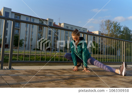 Attractive young woman stretching before her early morning run along the embankment of river. 106330938