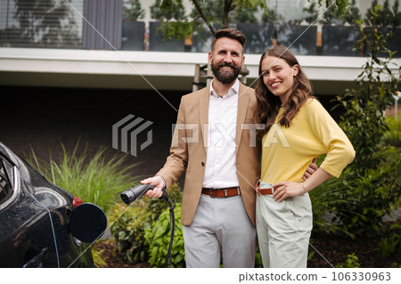 Happy young couple charging their electric car on the street. 106330963