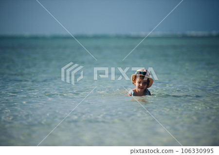 Portrait of a little girl swimming in a sea with straw hat on head. 106330995