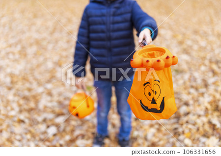 Unrecognizable boy holding pumpkin baskets in trick or treat season Unrecognizable boy holding pumpkin baskets in trick or treat season 106331656