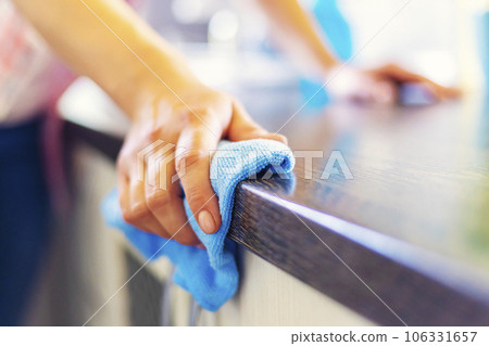 Woman hand cleaning the counter in the kitchen with a blue microfiber cloth 106331657