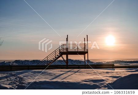 Sunset in winter on a beach with a lot of snow and with a rescue post in the center 106331659