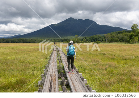 A female hiker walking on the wooden path of Ozegahara A female hiker walking on the wooden path of Ozegahara 106332566