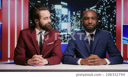 Broadcasters team presenting news live during night show tv program, using daily topics on reportage to discuss about important events. Diverse men presenters talking about global tv network. 106332744