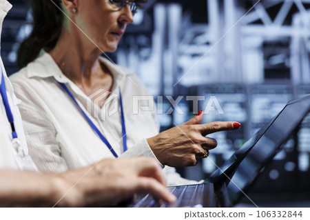 System administrators performing diagnostic assessments on supercomputers to detect problems with server farm units. Experts crosschecking checkup lists, looking for potential system hazards 106332844