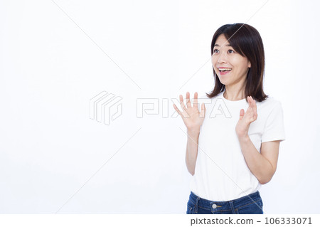 A woman in her thirties who is surprised with a smile in front of a white background 106333071