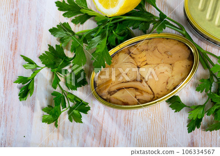 Canned tuna with parsley and lemon on a wooden table 106334567