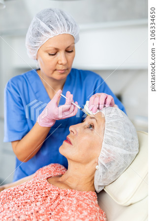 Qualified cosmetologist giving beauty injections for face skin rejuvenating and tightening for female client in aesthetic medicine office 106334650