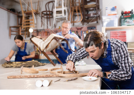 Portrait of middle-aged skillful repairman carpenter renovating chair furniture using tools in woodwork studio 106334717