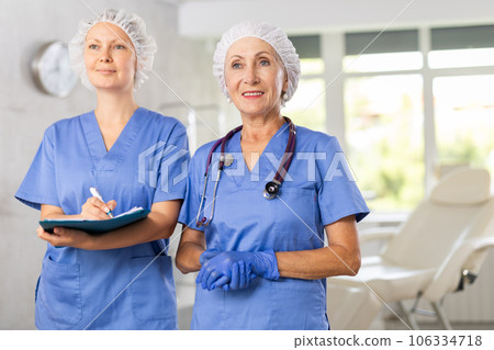 Portrait of two positive women doctors in blue uniform against the background of interior of clinic 106334718