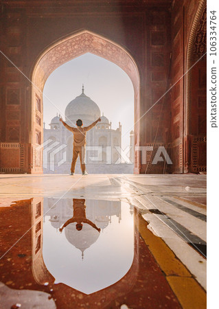 tourist standing in front entrance gate of Taj Mahal indian palace. Islam architecture. Door to the mosque tourist standing in front entrance gate of Taj Mahal indian palace. Islam architecture. Door to the mosque 106334764
