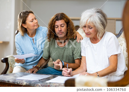 Positive couple and old woman taking notes on the sofa at home 106334768