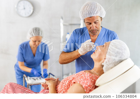 Woman applying rejuvenating treatments by male doctor. Woman applying rejuvenating treatments by male doctor. 106334804
