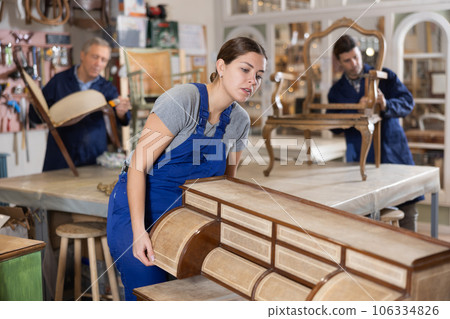Young female furniture workshop worker designing vintage chest of drawers 106334826