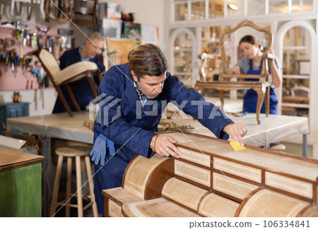 Male furniture maker sanding vintage commode in workshop 106334841