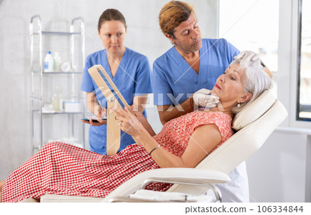 Plastic surgeon giving professional advice before facial contouring to senior woman 106334844