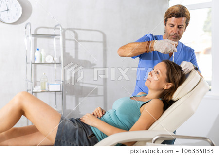 Male doctor makes injection in scalp of female patient Male doctor makes injection in scalp of female patient 106335033