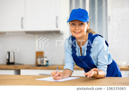Woman house cleaner making notes in kitchen 106335065
