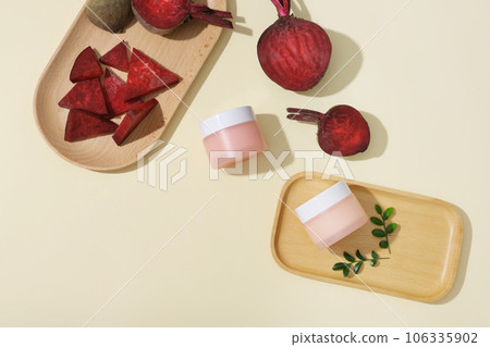 Wooden dishes featured beetroot cut in slices and an unbranded pink jar. Beetroot (Beta vulgaris) can help you eliminate dark circles under your eyes 106335902