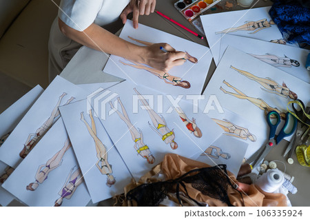 Faceless woman draws sketches of swimwear. Close-up of the hands of a fashion designer. Faceless woman draws sketches of swimwear. Close-up of the hands of a fashion designer. 106335924