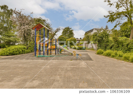 a playground in the middle of a residential area with lots of trees and bushes on either side of the road 106336109