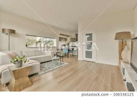 a living room with white walls and wood flooring in the center of the room is an open kitchen area 106336125
